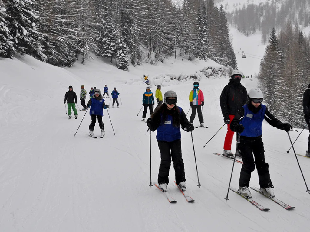 Kleine Gruppe steht auf der Piste beisammen.